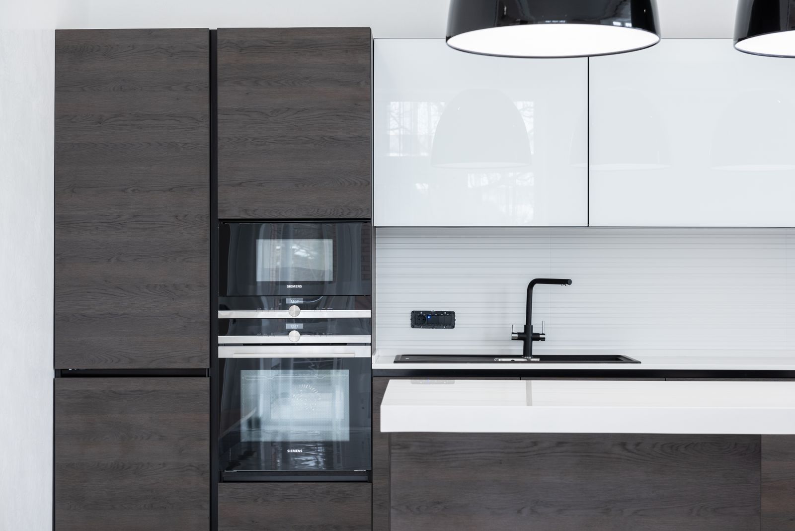 Modular kitchen with dark wood-grain tall units, high-gloss white cabinets and built-in ovens
