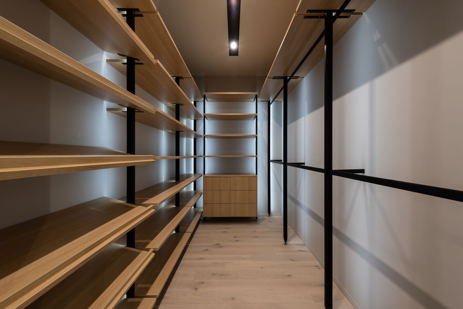 Walk-in wardrobe with open timber shelving, hanging rails and warm LED strip lighting